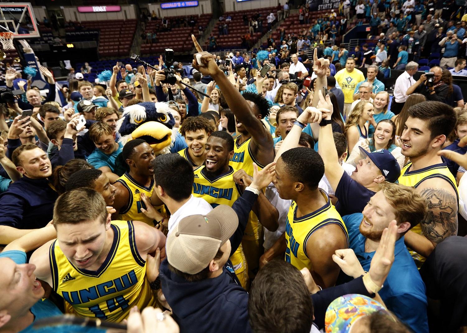 UNC Wilmington players, coaches and fans storm the court after defeating College of Charleston 78-69 at the end of an NCAA college championship basketball game in the Colonial Athletic Association tournament at the North Charleston Coliseum in North Charleston, S.C., Monday, March 6, 2017. (AP Photo/Mic Smith)