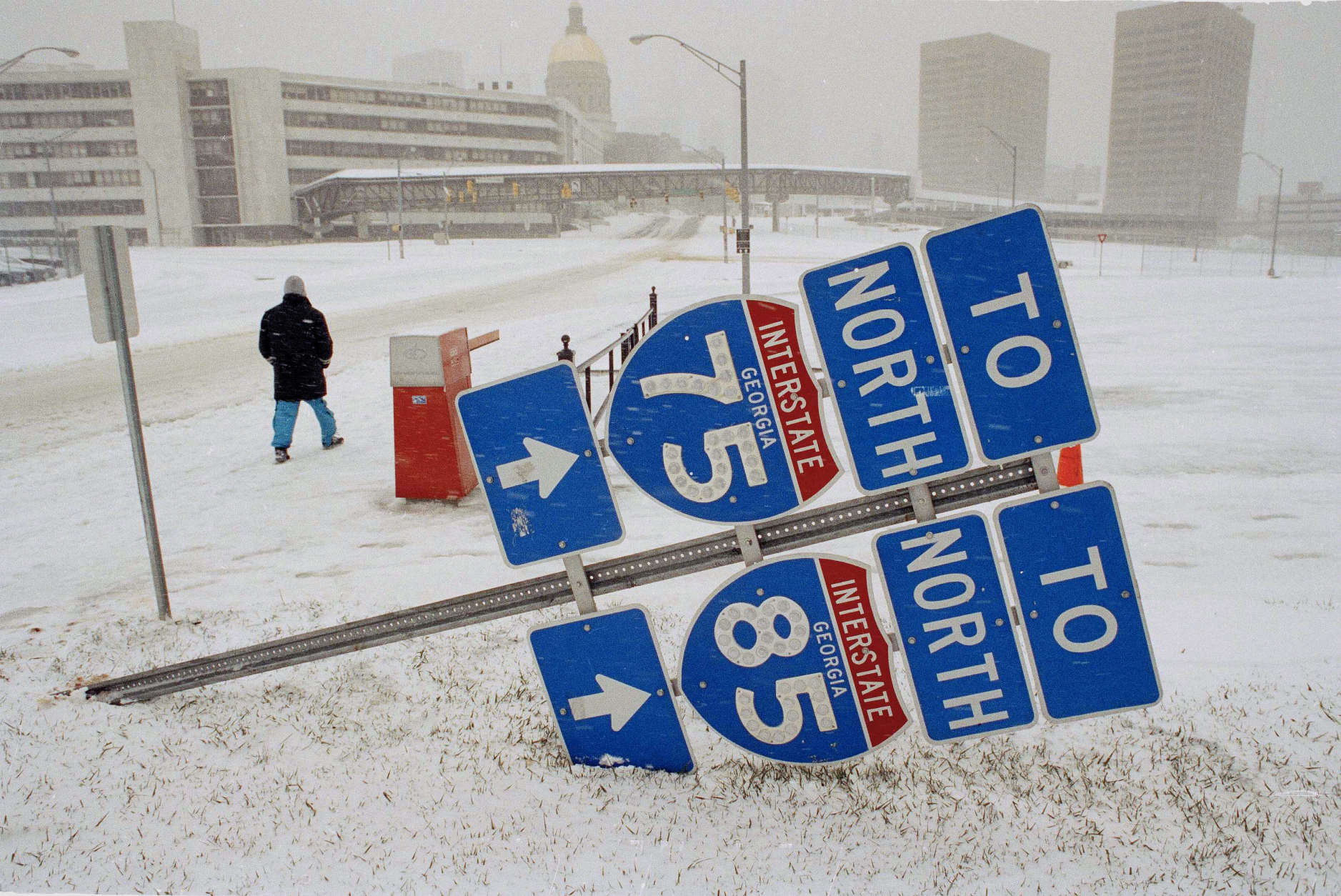 A pedestrian walks through the snow March 13, 1993, in Atlanta. Interstate signs were knocked down by the windy conditions. That snowstorm, which dumped 13.9 inches of snow at Dulles International Airport, enveloped the eastern third of the country. (AP Photo/Curtis Compton)