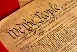 A parchment of the Constitution of the United States with a red background