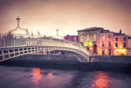 Vintage style historic Ha'penny Bridge and waterfront in Dublin Ireland at dusk