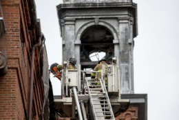 Firefighters work to cut pieces of damaged tin roof down after high winds damaged the roof of St. Aloysius Catholic Church at Gonzaga High School in Washington, Thursday, April 6, 2017. (AP Photo/Andrew Harnik)