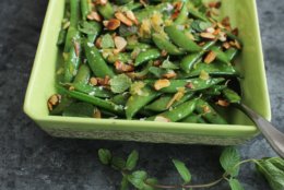 This Feb. 8, 2016 photo shows minty sugar snap peas with tangerine and toasted almonds in Concord, N.H. After a long winter of heavy foods, this simple, but delicious dish adds bright flavors and colors to springtime meals. (AP Photo/Matthew Mead)