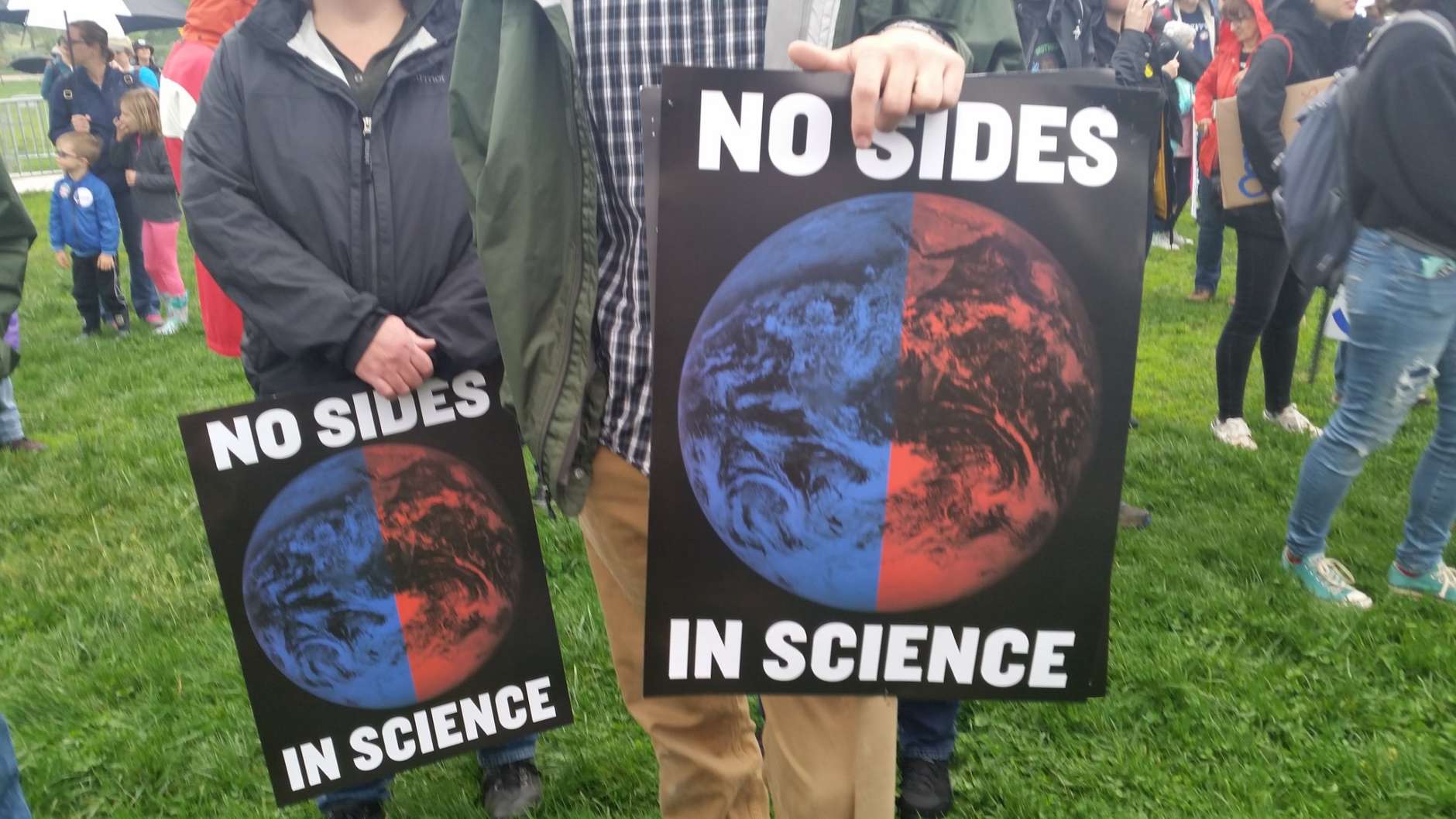 March for Science protesters hold signs at the National Mall. (WTOP/Kathy Stewart)