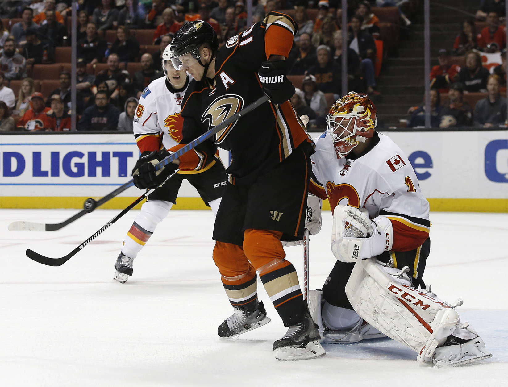 Anaheim Ducks right wing Corey Perry, left,, redirects the puck in front of Calgary Flames goalie Brian Elliott, right, as defenseman Michael Stone, rear, watches during the second period of an NHL hockey game in Anaheim, Calif., Tuesday, April 4, 2017. (AP Photo/Alex Gallardo)