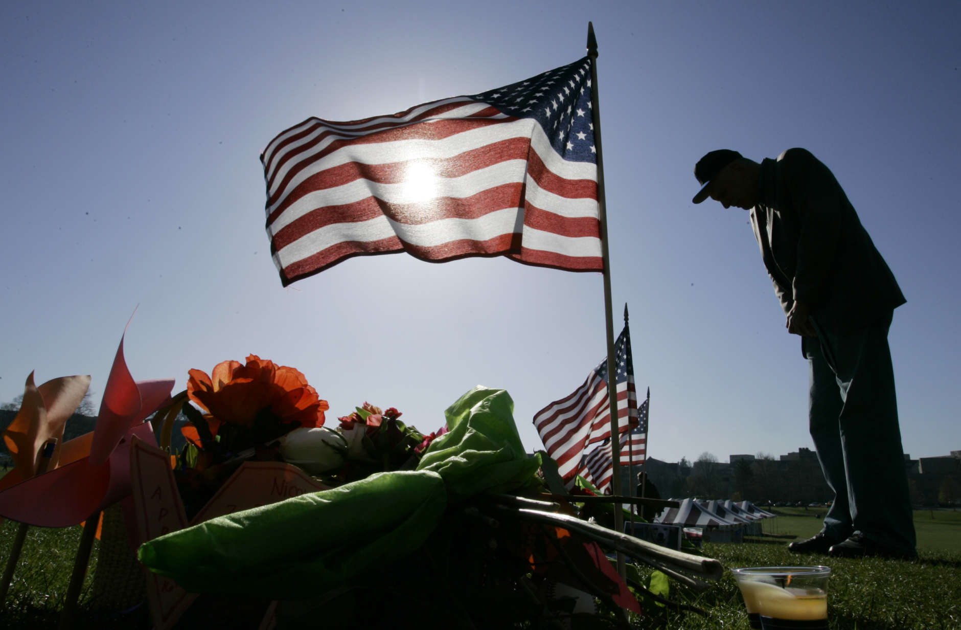 Flags are posted on the stones representing the shooting victims amongst flowers, candles, and notes of condolence at a makeshift memorial on the drill field of Virginia Tech in Blacksburg, Va., Saturday, April 21, 2007.  (AP Photo/Charles Dharapak)