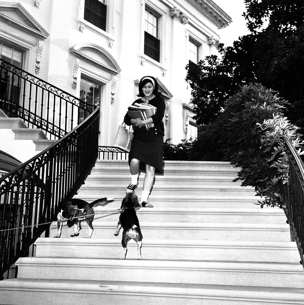 Luci, daughter of president and Mrs. Lyndon Johnson, stops on the White House steps to pet the family's beagles, Him and Her, as she leaves for school on Sept. 17, 1964. It is the first day of classes for Luci, who is in her senior year at National Cathedral School of Girls.(AP Photo)