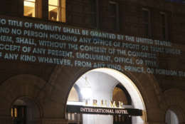 In this photo provided by Liz Gorman, taken Monday, May 15, 2017, President Donald Trump’s Washington hotel is briefly illuminated with projected messages by Robin Bell, a Washington-based artist and filmmaker. Bell says he used a video projector to splash the words across an entrance to the hotel in protest of what he called Trump’s foreign ties. He says the projector ran for about 10 minutes before a security guard asked him to stop. (Liz Gorman via AP)