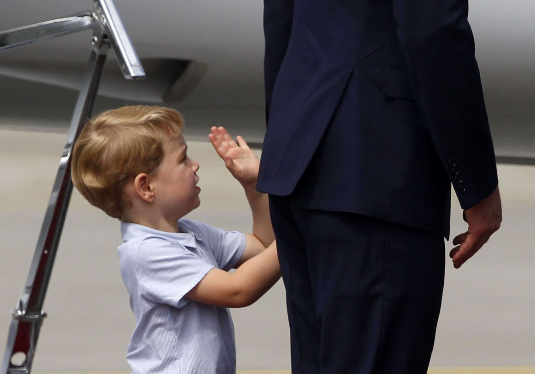 Britain's Prince William, right, holds the hand of his son Prince George as they leave the airport in Warsaw, Poland, Wednesday, July 19, 2017. The British royal couple is in Poland with their children on a goodwill visit intended to seal friendly ties after Britain leaves the European Union. (AP Photo/Czarek Sokolowski)