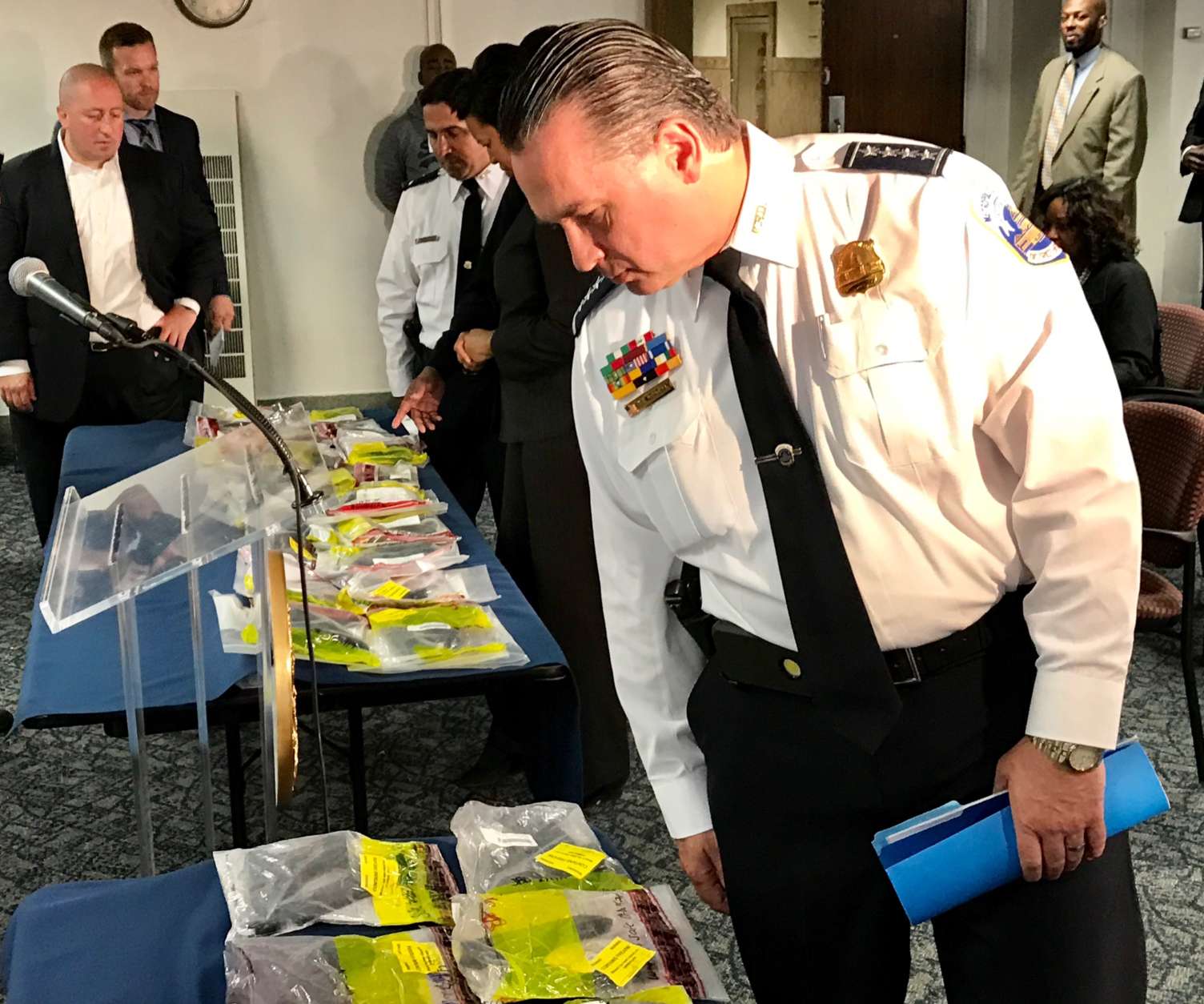 D.C. Police Chief Peter Newsham surveys the illegal firearms pulled off the streets and packaged in evidence bags after a press conference May 10, 2017. (WTOP/Megan Cloherty)