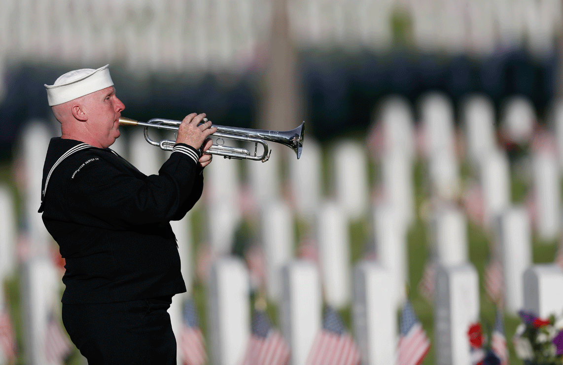 Playing a tribute to veterans at gravesites to mark the Memorial Day holiday, retired U.S. Navy yeoman Mark Stallins of Denver performs in Fort Logan National Cemetery on Sunday, May 28, 2017, in southwest Denver. (AP Photo/David Zalubowski)