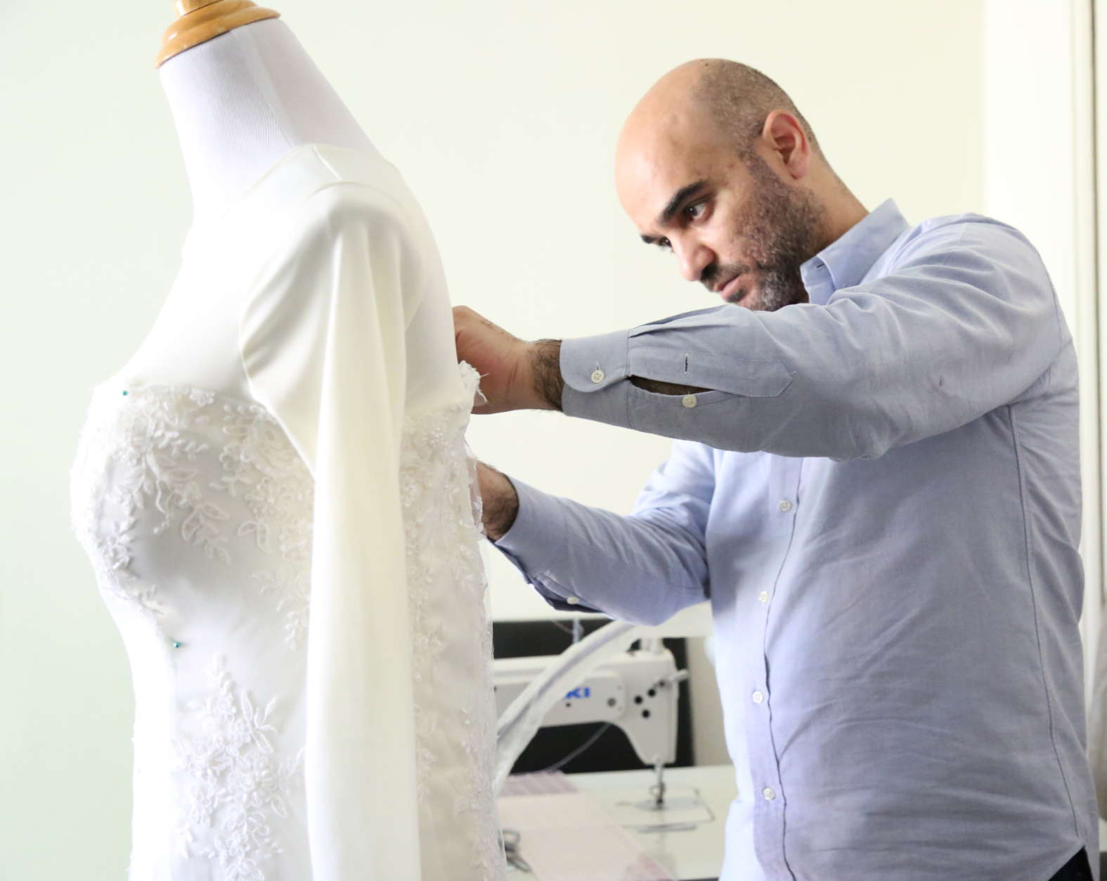 Picture of Nader Briman makes some alterations on a long-sleeve lace wedding dress.