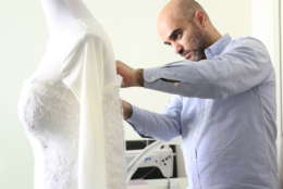Picture of Nader Briman makes some alterations on a long-sleeve lace wedding dress.
