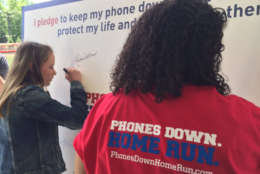 Students at McLean High School sign a pledge against distracted driving that is part of the "Phones Down. Home Run" campaign. (WTOP/Kristi King)