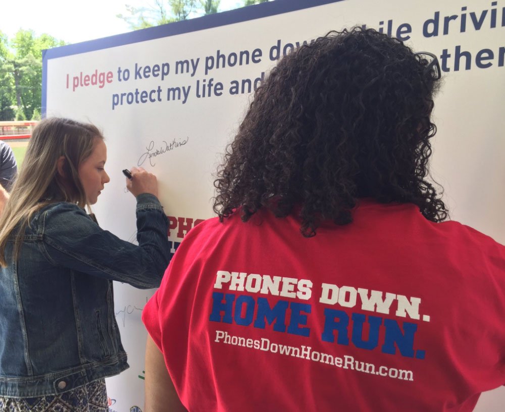 Students at McLean High School sign a pledge against distracted driving that is part of the "Phones Down. Home Run" campaign. (WTOP/Kristi King)