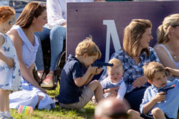 Britain's Kate, the Duchess of Cambridge, left, sits with Prince George and other unidentified spectators as they watch Prince William take part in the Maserati Royal Charity Polo Trophy at the Beaufort Polo Club, in Tetbury, England, Sunday June 10, 2018. (Steve Parsons/PA via AP)