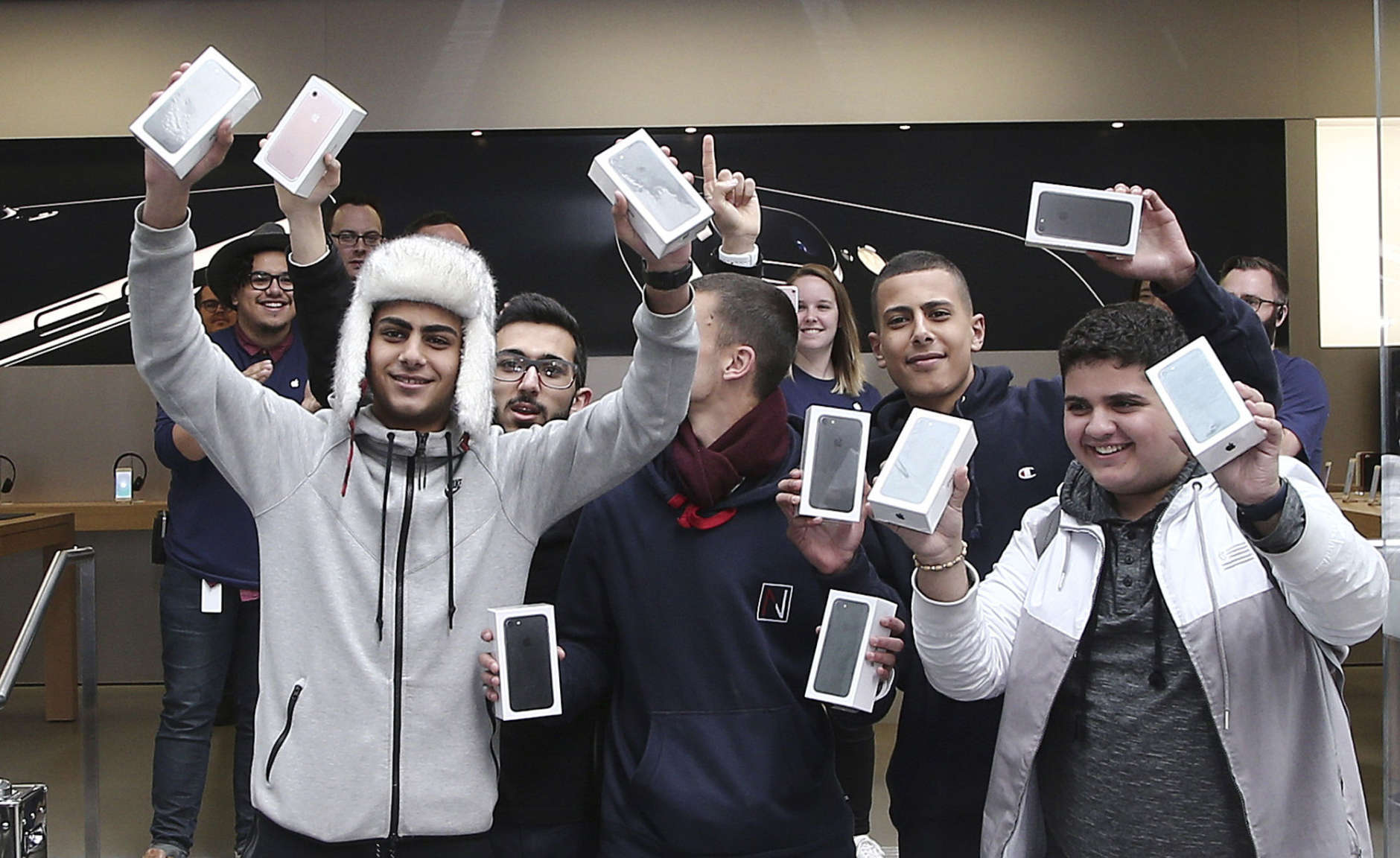 The first group of customers including Bishoy Behman, left, and Marcus Barsoum, right, hold up their purchases at the Apple store in Sydney, Australia, Friday, Sept. 16, 2016. Behman, a 17-year-old high school student who has camped on the street in front of the store since Wednesday morning was the first retail customer in the world to purchase the new model phone. (AP Photo/Rob Griffith)