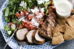 In this image taken on June 10, 2013, grilled pork tenderloin with watermelon-arugula salad is shown served on a platter in Concord, N.H. (AP Photo/Matthew Mead)