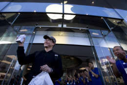 Apple employees applaud as the first customer proudly shows off his new iPhone 5S outside an Apple store in Wangfujing shopping district in Beijing, China on Friday, Sept. 20, 2013. Apple released the iPhone 5S and 5C models on Friday. (AP Photo/Andy Wong)