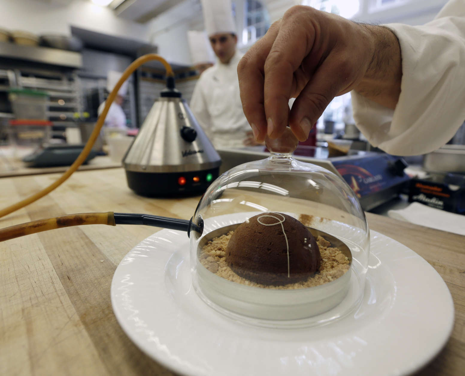In this image taken on Friday, Sept. 14, 2012, cinnamon aroma is added to a peanut butter and milk chocolate dome dessert at the Culinary Institute of America in Hyde Park, N.Y. This esteemed cooking school north of New York City is dramatically pumping up science instruction, saying that tomorrow's chefs will need more technical know-how in the age of molecular gastronomy and sous-vide. (AP Photo/Mike Groll)