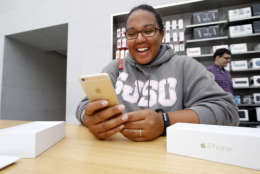 Amanda Germain smiles after buying a iPhone 6 at the Apple Store for during the launch and sale of the new iPhone 6 on Friday, Sept 19, 2014, in Palo Alto, Calif. (AP Photo/Tony Avelar)