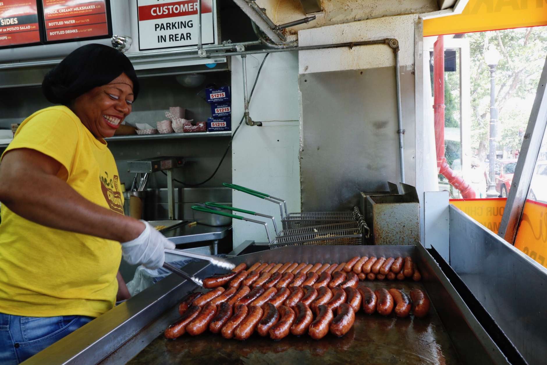 Angela Powell makes sure the dogs are just right at Ben's Chili Bowl on U Street. (WTOP/Kate Ryan)