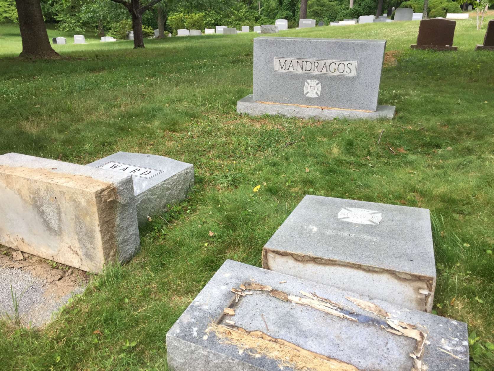 The toppled tombstone in the foreground belongs to Prince George's County Volunteer Firefighter Dennis M. Mandragos, who died with two other firefighters in a head-on collision in 1973, according to Dick Bergren, the acting sextant of the cemetery. The standing Mandragos stone is for Dennis' father, who also was with the fire department and was a Navy commander, according to Bergren. "I knew all these folks." (WTOP/Kristi King)