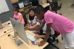 Phylisha Bower works with other girls in the class on editing their games with instructor Nina Tungjairob, who is seated in the middle. (WTOP/Kristi King)