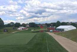 You can take in the par 3 17th from above or from the green below, but you needn't follow the action down the hill to make it to 18, which you can reach by cutting behind the grandstand on the right. (WTOP/Noah Frank)