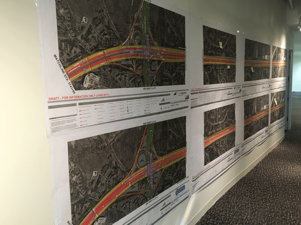 Updated design plans for Interstate 66 toll lanes hang above VDOT’s original designs that were published last year in the office of the private company designing and building two toll lanes in each direction between the Beltway and Gainesville. (WTOP/Max Smith)