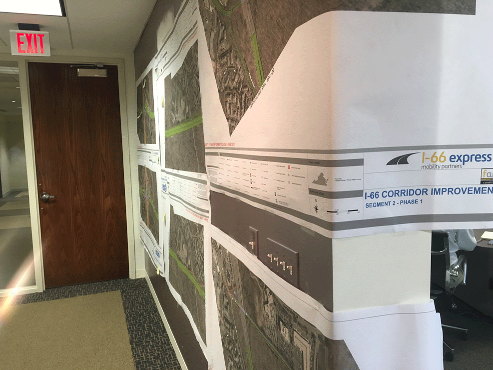 Updated design plans for Interstate 66 toll lanes hang above VDOT’s original designs that were published last year in the office of the private company designing and building two toll lanes in each direction between the Beltway and Gainesville. (WTOP/Max Smith)