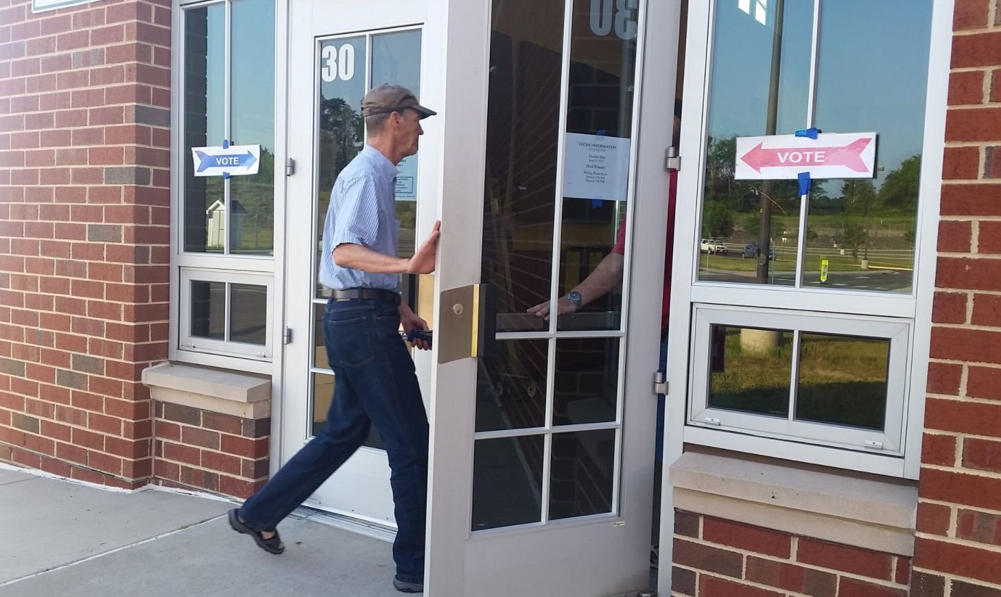 Pictured is a man opening a door to a voting facility in Virginia