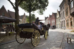 Tourists ride in a horse drawn carriage past the Halve Maan Brewery in Bruges, Belgium on Thursday, May 26, 2016. The brewery has recently created a beer pipeline which will ship beer straight from the brewery to the bottling plant, two kilometers away, through underground pipes running between the two sources. (AP Photo/Virginia Mayo)