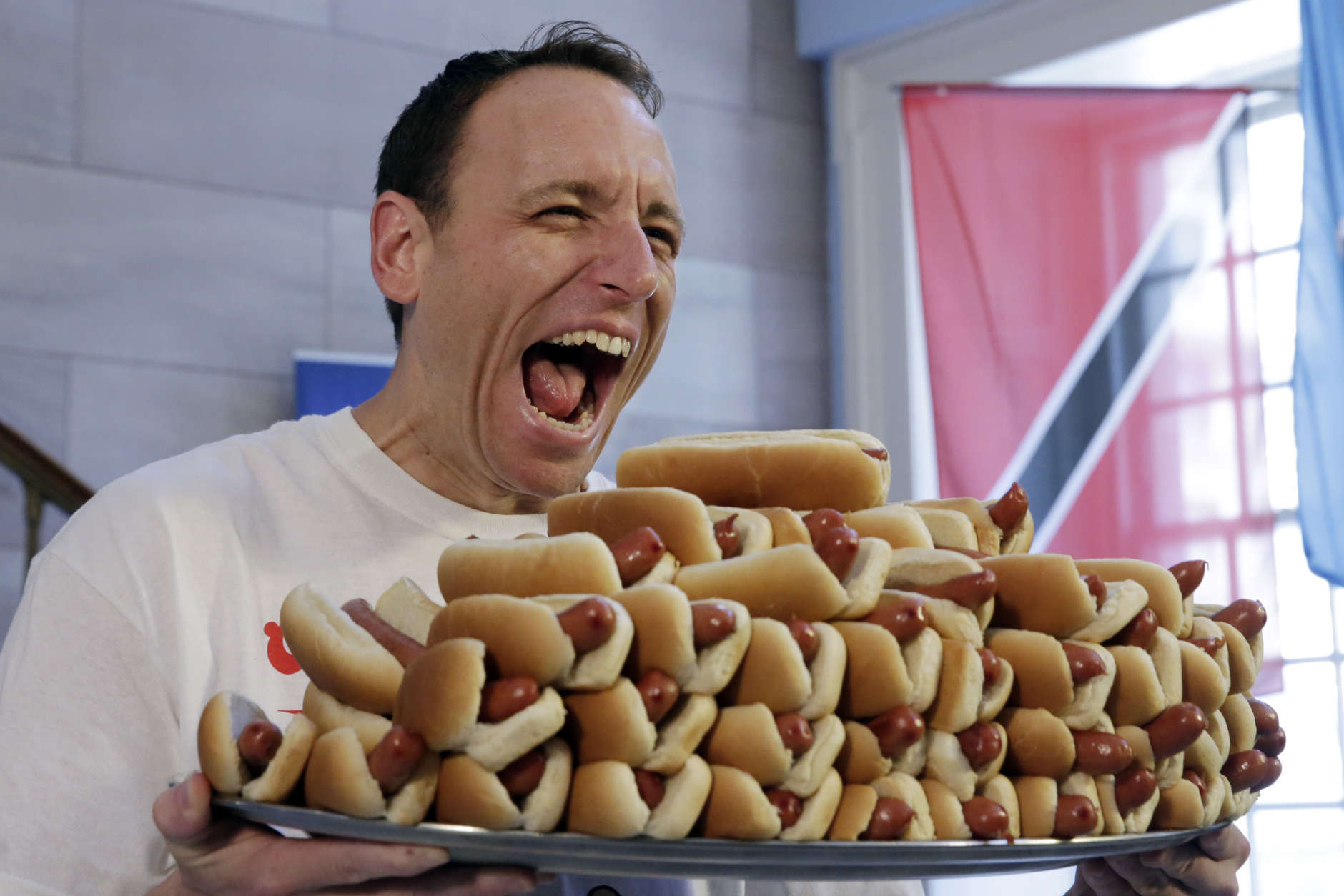 Current men's champion Joey Chestnut, of San Jose, Calif., holds a tray of hot dogs during the weigh-in for the 2017 Nathan's Hot Dog Eating Contest, in Brooklyn Borough Hall, in New York, Monday, July 3, 2017. Chestnut weighed-in at 221.5 pounds. (AP Photo/Richard Drew)