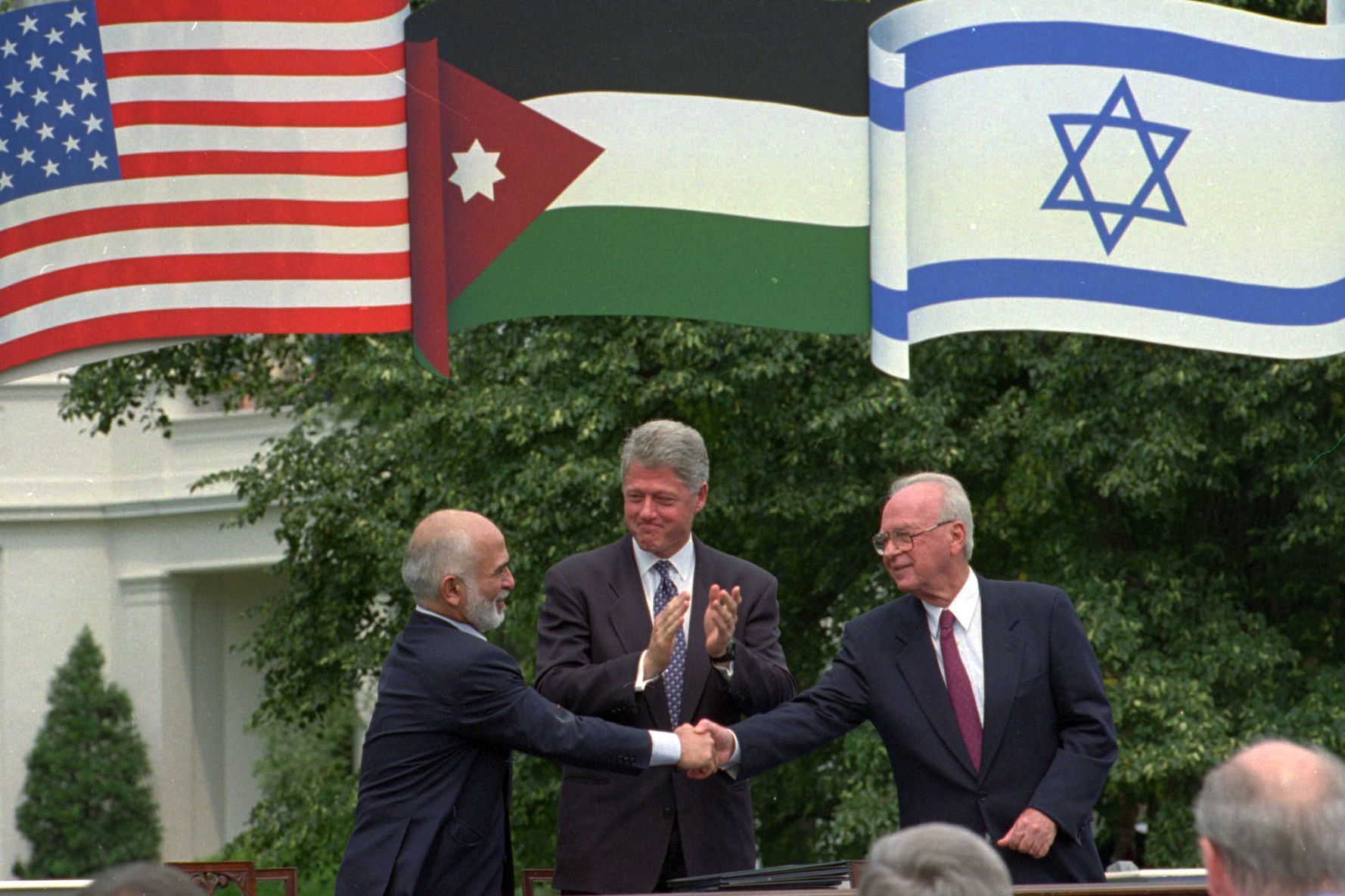 FILE- in this Monday, July 25, 1995 file photo U.S. President Bill Clinton applauds as King Hussein of Jordan, left, and Israeli Prime Minister Yitzhak Rabin, right, shake hands after signing a declaration in Washington, D.C., ending 46-years of hostilities between the two countries. A diplomatic standoff between Israel and Jordan over a deadly shooting at Israel's embassy in the kingdom once again tests the strategically critical yet turbulent ties forged in a 1994 peace treaty.(AP Photo/Greg Gibson, File)