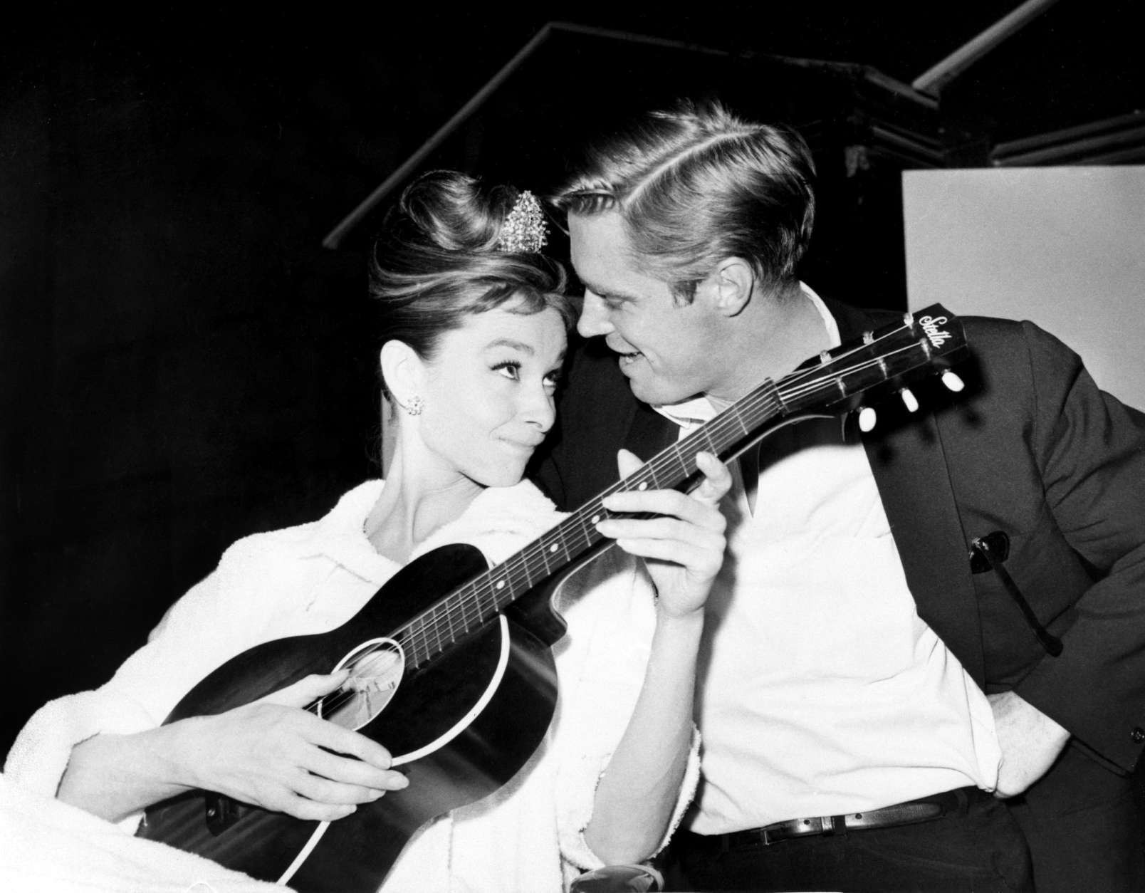 British actress Audrey Hepburn strums a guitar with her co star George Pappard between takes on the set of "Breakfast in Tiffany's" at a film studio in Hollywood on Dec. 7, 1960. (AP Photo)