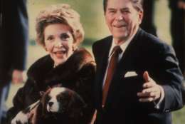 **FILE**   This December 1986 file photo shows first lady Nancy Reagan holding the Reagans' pet Rex, a King Charles spaniel, as she and President Reagan walk on the White House South lawn. (AP Photo/Dennis Cook, FILE)