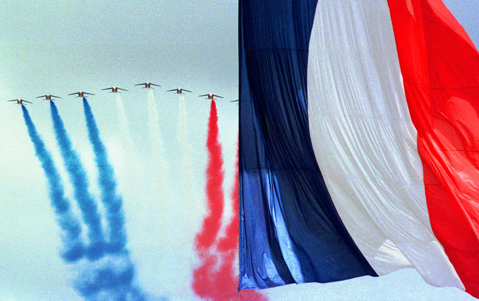 "Patrouille de France" jet fighters fly blue white and red smoke past a giant French flag over the Champs Elysees in Paris Tuesday July 14 1998 on the occasion of the traditional Bastille day military parade. (AP PHOTO/JeromeDelay)