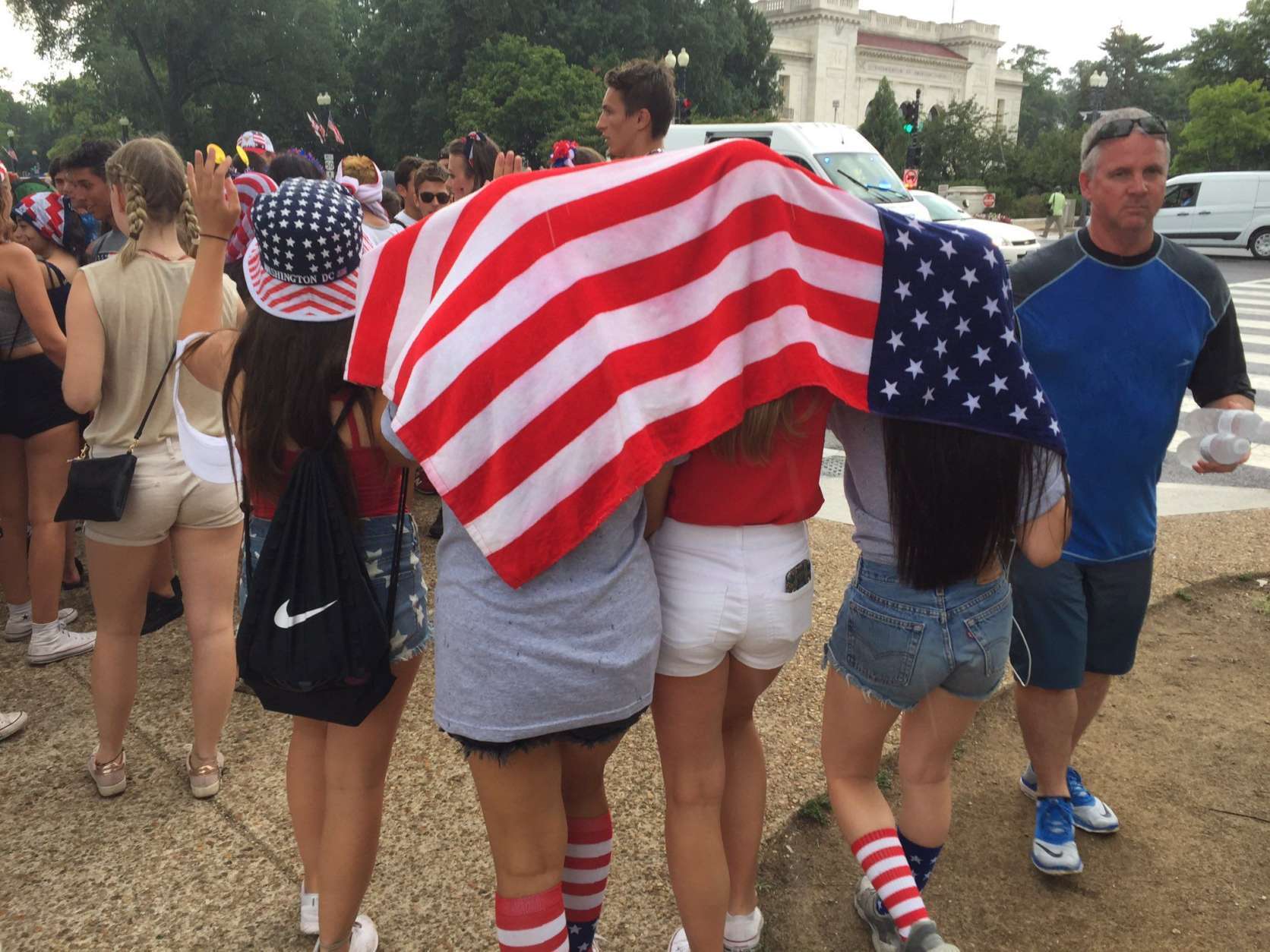 Some spectators used Old Glory to stay dry during some surprise showers. (WTOP/Michelle Basch)