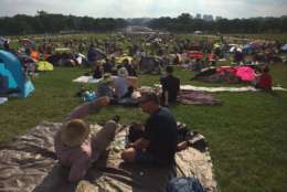 Spectators get settled near the Washington Monument early Tuesday evening. (WTOP/Michelle Basch)