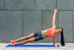 Fit young woman doing sideplanks, strengthening her core, working out on a mat, lifestyle and health concept