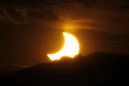 FILE - In this May 20, 2012, file photo, the annular solar eclipse is seen as the sun sets behind the Rocky Mountains from downtown Denver. Destinations are hosting festivals, hotels are selling out and travelers are planning trips for the total solar eclipse that will be visible coast to coast on Aug. 21, 2017. A narrow path of the United States 60 to 70 miles wide from Oregon to South Carolina will experience total darkness, also known as totality. (AP Photo/David Zalubowski, File)