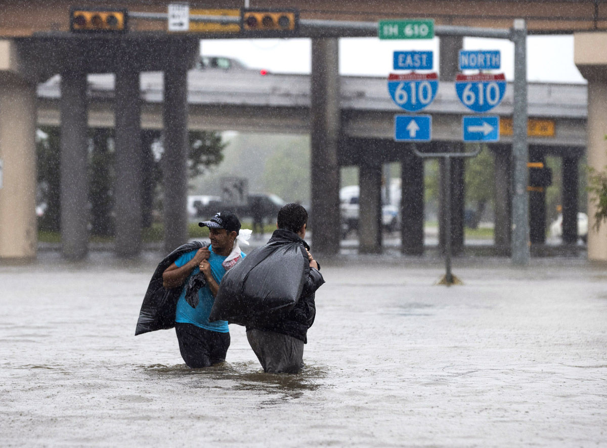 HOUSTON, TX - AUGUST 28:  Local apartment residents cross high water on North Braeswood Blvd to escape the flooding from Hurricane Harvey August 28, 2017 in Houston, Texas. Harvey, which made landfall north of Corpus Christi late Friday evening, is expected to dump upwards to 40 inches of rain in areas of Texas over the next couple of days.  (Photo by Erich Schlegel/Getty Images)