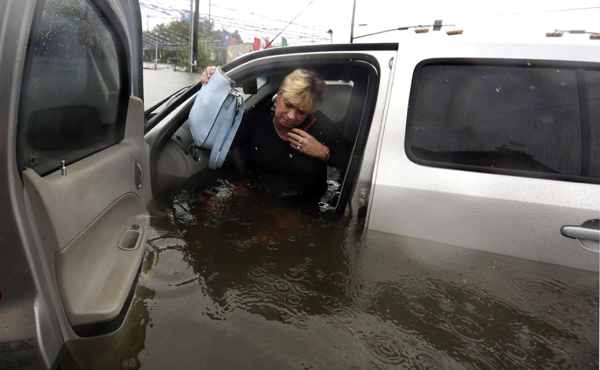 Rhonda Worthington talks on her cell phone with a 911 dispatcher as he gets out of her car after her vehicle become stalled in rising floodwaters from Tropical Storm Harvey in Houston, Texas, Monday, Aug. 28, 2017. Worthington said she thought the water was low enough to drive through before the vehicle started to float away. (AP Photo/LM Otero)