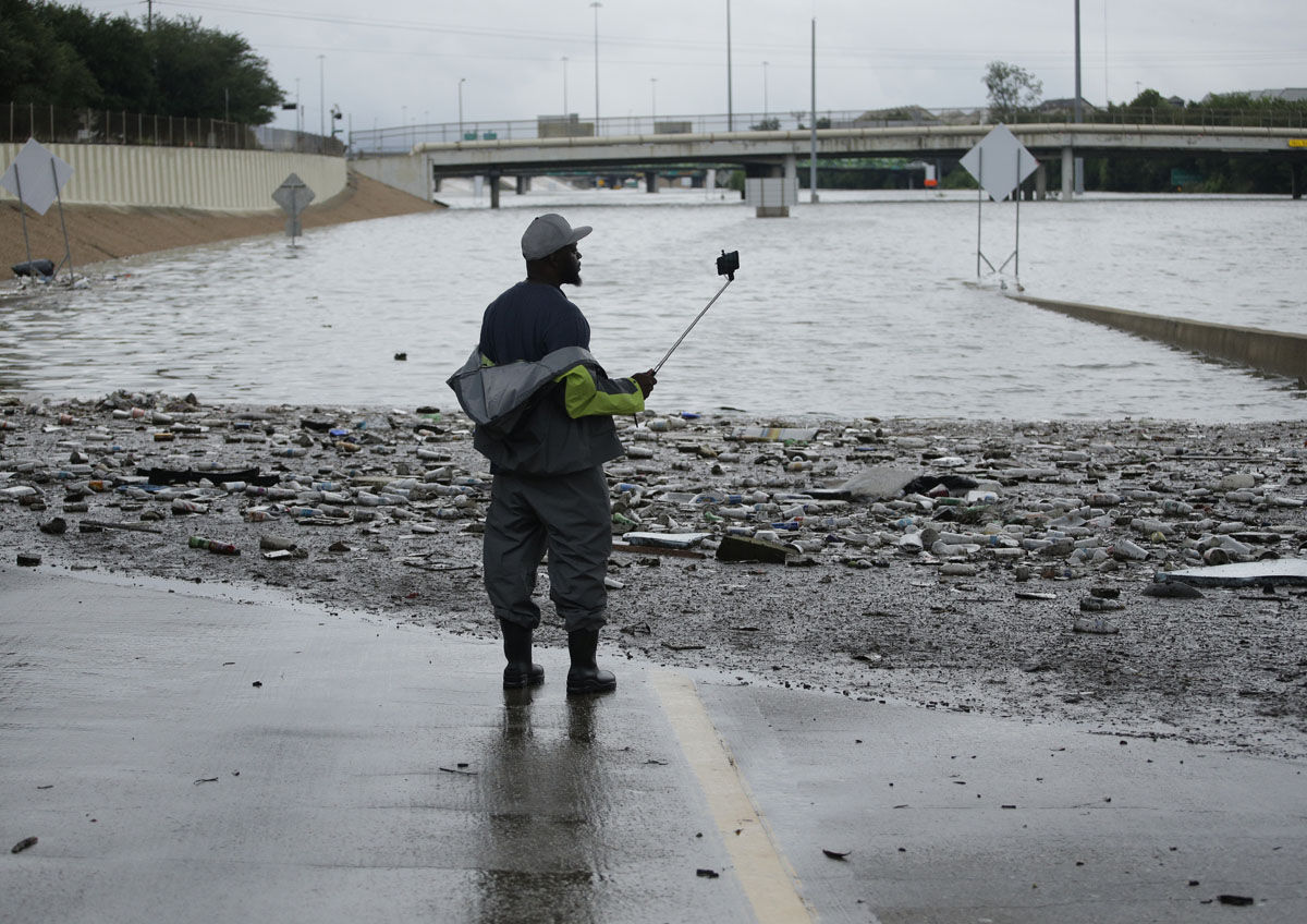 A man takes photos of a freeway flooded by Tropical Storm Harvey on Sunday, Aug. 27, 2017, near downtown Houston, Texas. (AP Photo/Charlie Riedel)