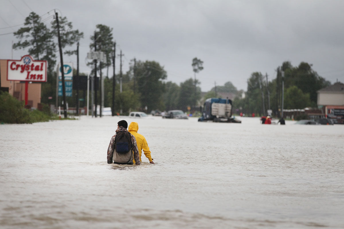 HOUSTON, TX - AUGUST 29:  People make their way out of a flooded neighborhood after it was inundated with rain water following Hurricane Harvey on August 29, 2017 in Houston, Texas. Harvey, which made landfall north of Corpus Christi August 25, has dumped nearly 50 inches of rain in and around areas Houston.  (Photo by Scott Olson/Getty Images)