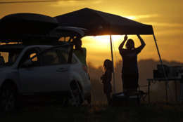 A family sets up a tent at their campsite at sunrise for the solar eclipse Monday, Aug. 21, 2017, on the Orchard Dale historical farm near Hopkinsville, Ky. The location, which is in the path of totality, is also at the point of greatest intensity. (AP Photo/Mark Humphrey)