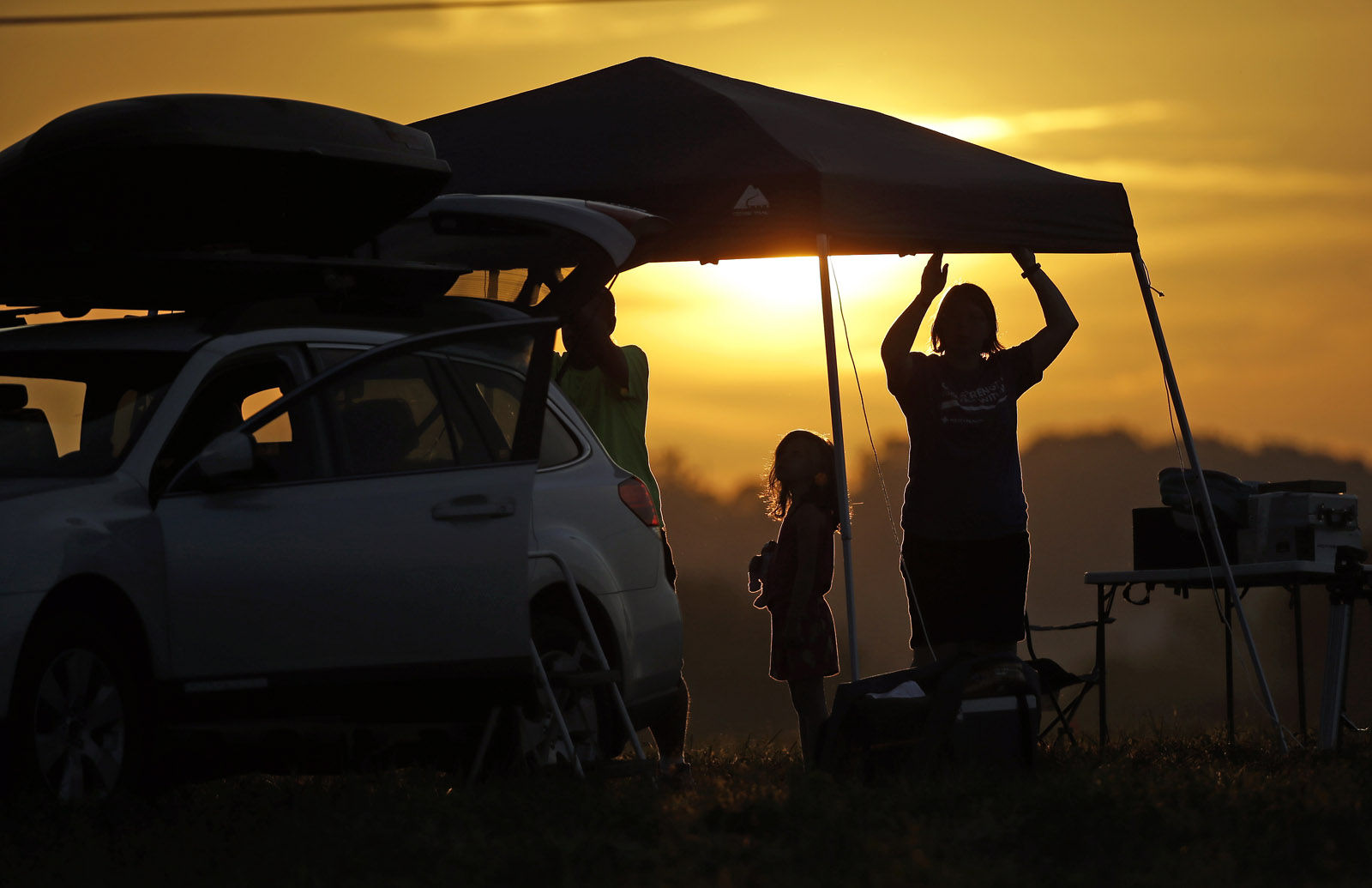 A family sets up a tent at their campsite at sunrise for the solar eclipse Monday, Aug. 21, 2017, on the Orchard Dale historical farm near Hopkinsville, Ky. The location, which is in the path of totality, is also at the point of greatest intensity. (AP Photo/Mark Humphrey)