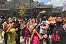 Visitors at the Air and Space Museum look up at the sky to get a glimpse of the eclipse. (WTOP/Megan Cloherty)