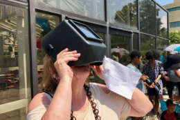 A woman watches the eclipse through a safety visor at the Air and Space Museum. (WTOP/Megan Cloherty)