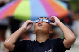 Ezra Packham, of Jacksonville, Fla., looks through his solar glasses in preparation for the solar eclipse Monday, Aug. 21, 2017, on the beach at Isle of Palms, S.C. Ezra and his family said the wanted to come to the Isle of Palms because they wanted to be on the beach and the city of Isle of Palms was giving away solar glasses. (AP Photo/Mic Smith)
